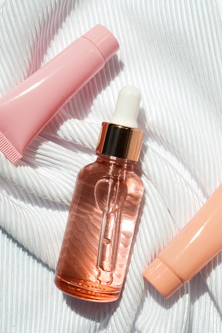 Serum Bottle and Cosmetic Tubes on White Fabric Flatlay