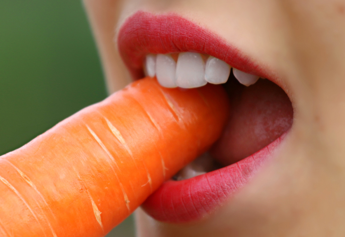Woman Biting Raw Carrot